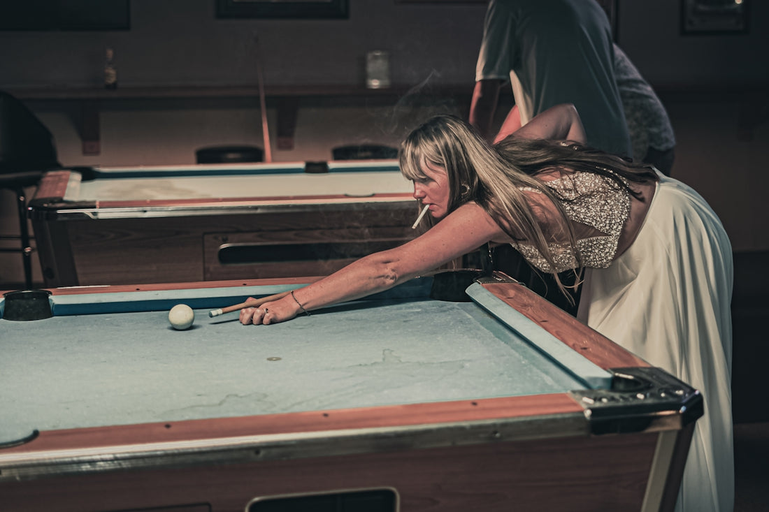 a woman leaning over a pool table to hit a ball
