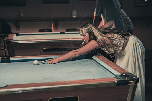a woman leaning over a pool table to hit a ball