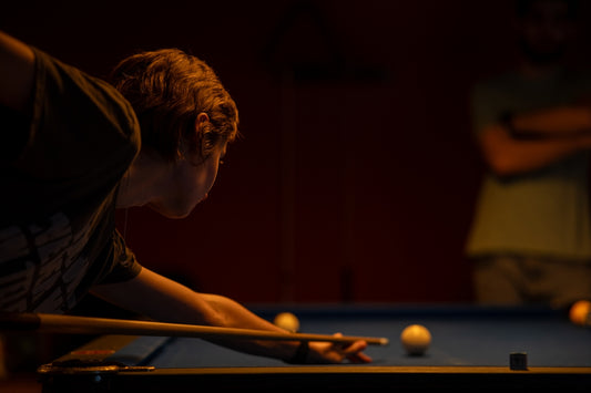 a man leaning over a pool table with a cue in his hand