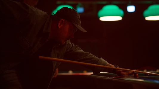 A man playing pool in a dark room