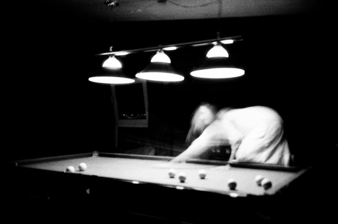 A man leaning over a pool table in a dark room