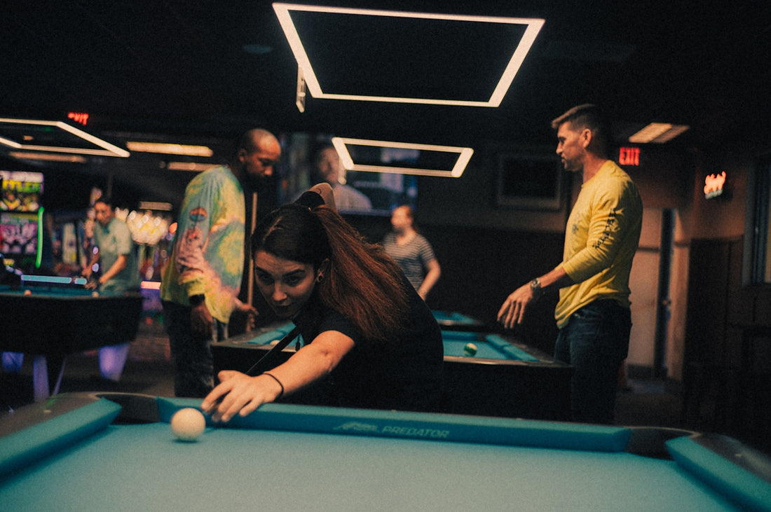 A group of people standing around a pool table