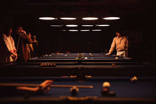 A group of people standing around a pool table