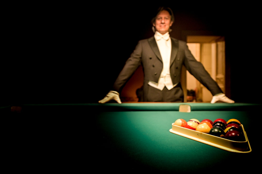 A man in a tuxedo smiles over a pool table.