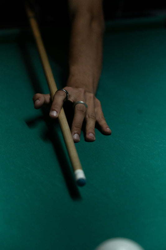 Hand holding a pool cue over green felt