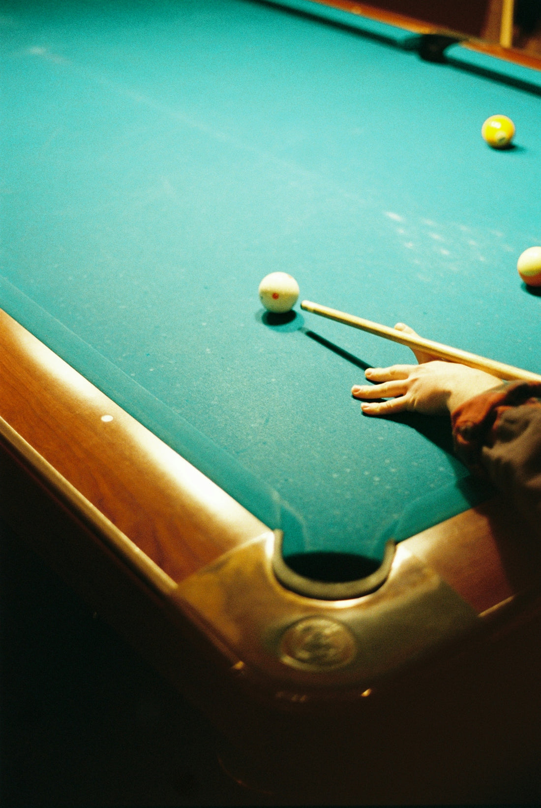 A person plays billiards on a green felt table.
