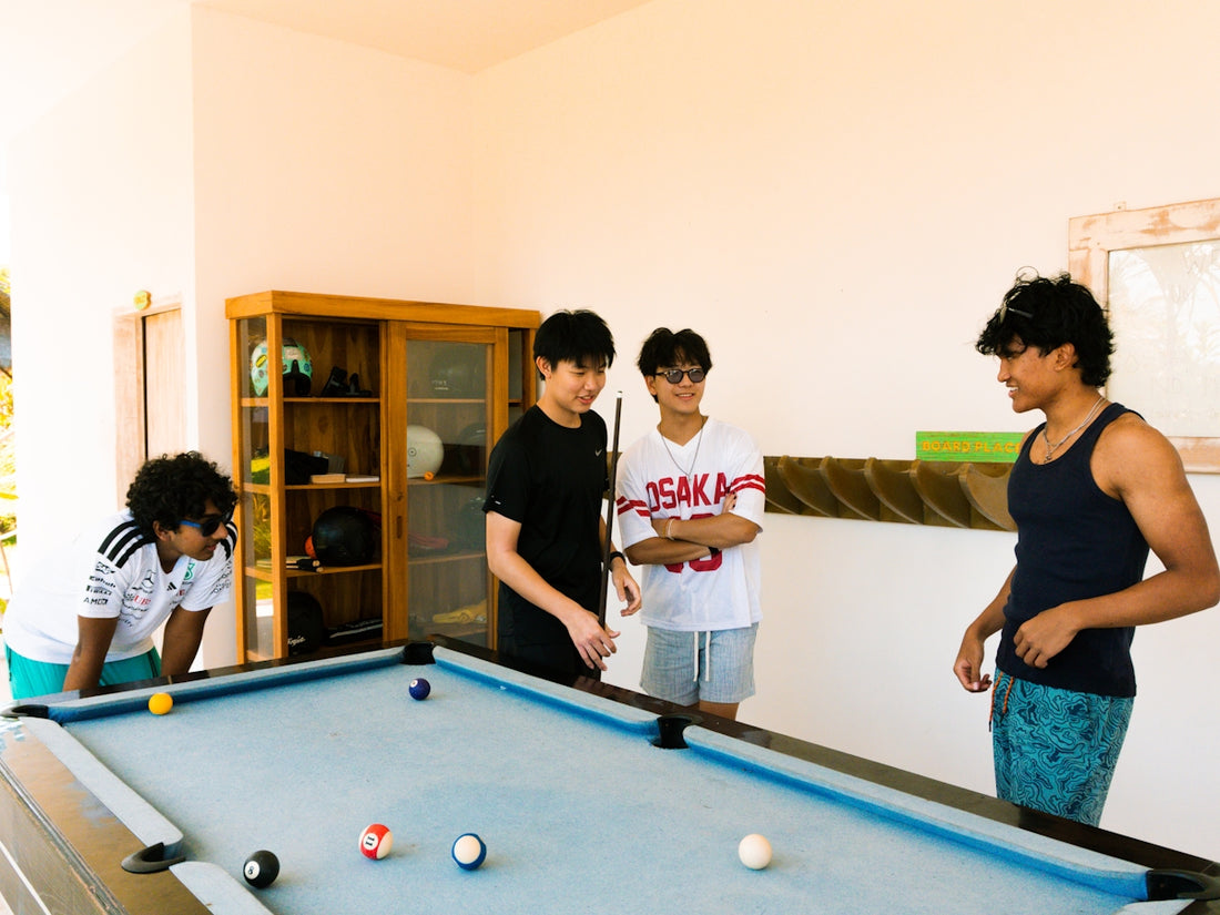 Four young men playing pool indoors.